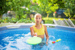 © Ljustina - Girl playing with water racket in backyard swimming pool