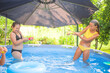 © Ljustina - Two happy girls having fun playing with water guns in backyard swimming pool