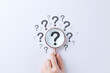 © Sandwish - Question mark and root cause analysis concept. Hand holding magnifying glass over large question mark surrounded by smaller ones on white background, symbolizing analysis and problem-solving. solution