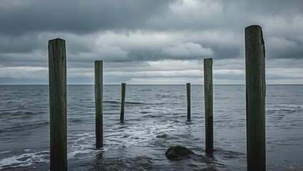 Wall Mural - Tranquil North Sea Scene with Gray Clouds and Weathered Wooden Poles Leading into the Distance Over Calm Water Surface