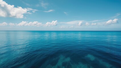 Wall Mural - Calm ocean water under a clear blue sky with a few clouds in the distance, perfect for tranquil backgrounds and seascape themes