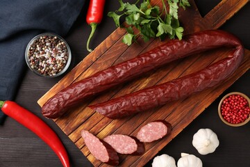 Wall Mural - Delicious thin smoked sausage and spices on dark wooden table, flat lay