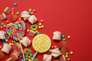 Wall Mural - Many different tasty candies and marshmallows on red background, flat lay. Space for text