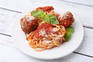 Wall Mural - Delicious pasta with meatballs, cheese and basil on light wooden table, closeup