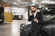 © sofiko14 - Middle-aged Caucasian male in a suit using smartphone in a parking garage. Professional appearance and modern environment represent business and communication concepts.