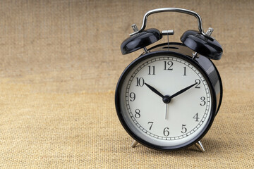 A classic retro alarm clock with a metal bell on brown background marking morning time.