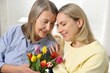 © New Africa - Smiling daughter congratulating her mom with bouquet of tulips at home. Happy Mother's Day