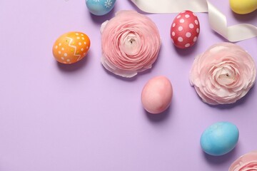 Wall Mural - Easter eggs, ranunculus flowers and ribbon on lilac background, flat lay. Space for text