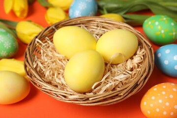 Wall Mural - Easter eggs and beautiful tulips on orange background, closeup