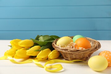 Wall Mural - Easter eggs, ribbon and beautiful tulips on white wooden table