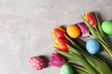 Wall Mural - Easter eggs and beautiful tulips on grey table, flat lay. Space for text