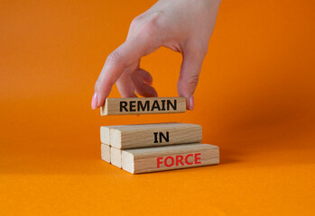 Remain in Force symbol. Concept words Remain in Force on wooden blocks. Businessman hand. Beautiful orange background. Business and Remain in Force concept. Copy space