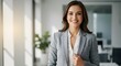 © TJ_Designs - beautiful smile woman wearing a business suit, standing in the office, sunshine, with a little bit of blurred background with copy space