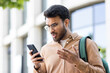 © Liubomir - Upset student with phone in hand received notification with bad news, man with smartphone in hand outside university campus, nervous and disappointed.