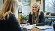 © EddieSnapix - A social worker smiles while interacting with a client in a community service office. They discuss important topics, surrounded by informational materials and a plant