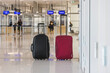 © 24K-Production - Red-brown rolling travel suitcase at the airport terminal with blurred passengers in the background. Journey, luggage, and aerodrome concepts.