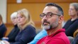 © Mind - Attentive Middle Aged Man in Maroon Shirt at a Meeting