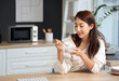 © Pixel-Shot - Pretty young Asian woman eating tasty yogurt with blueberries at home