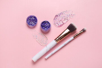 Wall Mural - Makeup brushes and jars of glitter with strokes on pink background