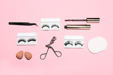 Wall Mural - Different false eyelashes with tools and mascara on pink background