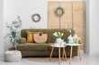 © Pixel-Shot - Interior of light living room with sofa, folding screen and Easter wreaths