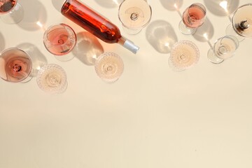 Wall Mural - Delicious rose wine in glasses and bottle on beige background, flat lay. Space for text