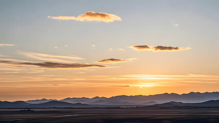 Wall Mural - Serene Sunset over Mountains. The scene at sunset. The sky is dyed orange-yellow. A few clouds are floating in it. The distant continuous mountains have a clear outline under the afterglow of the sett