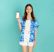 © sitthiphong - Portrait of young Asian woman in summer wearing floral shirt holding and holding smartphone mockup of blank screen and smiling on blue background.
