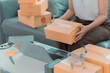 © MrAshi - A young Asian woman who runs a folding cardboard box business prepares packages for delivery from her online shopping, small SME business. Close-up photo