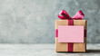 © Stock Media Labs - A beautifully wrapped gift box with a pink ribbon and tag, set against a textured gray background, symbolizing celebration.
