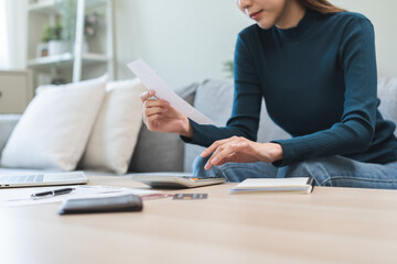 Wall Mural - Debt concept stressed asian young business woman using calculator to calculate expenses of monthly, female hand holding bills and receipt for to payment on table at home. Financial, finance of banking