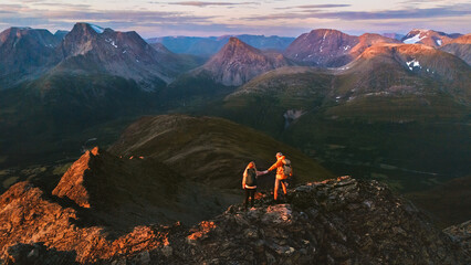Wall Mural - couple hiking in mountains of norway aerial view friends adventurers man and woman climbing, active 