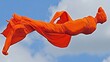 © Windi - Orange cloth figure floats, sky backdrop, festival