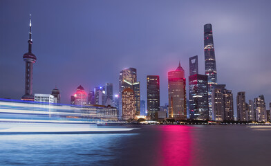 Wall Mural - Shanghai colorful skyline with motion speed light of passing ferry in the foreground at night - Shanghai, China