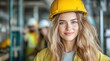 © Anna - young woman wearing a yellow hard hat and safety gear stands in a construction site, smiling confidently. Colleagues are working in the background, creating a lively atmosphere