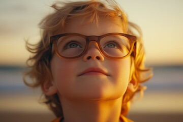 Sticker - Child gazes thoughtfully towards the sky during a sunset at the beach while wearing glasses