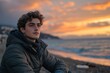 © c80 - Young man enjoying a serene sunset on the beach with waves gently lapping at the shore
