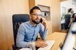 © Dusan Petkovic - Portrait of a businessman sitting at his workstation at office in corporate firm with cellphone in hands and having phone call.