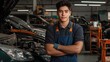 © Attasit - A young worker wearing blue overalls, focused on auto body repair in a busy garage.