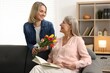 © New Africa - Smiling daughter congratulating her mom with bouquet of tulips at home. Happy Mother's Day