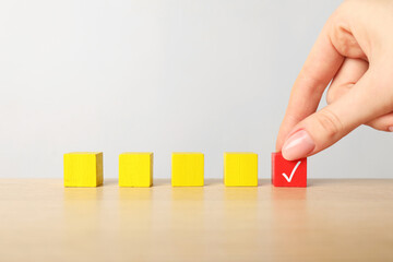 Woman taking red cube with check mark at table, closeup