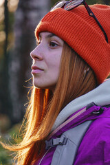 Wall Mural - a young woman in profile in the forest . A girl in bright outdoor clothes looks away, hiking and an active lifestyle