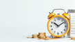 © Tondone - yellow alarm clock sits beside calendar and stack of coins, symbolizing time management and financial planning. scene conveys sense of organization and productivity