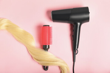 Wall Mural - Stylish round brush, lock of blonde hair and hairdryer on pink background, flat lay