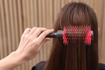 Wall Mural - Hairdresser styling client's hair with round brush in salon, closeup