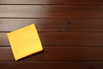 Wall Mural - Yellow napkin on wooden table, top view. Space for text