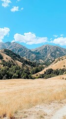 Wall Mural - a scenic view of mountains under a bright blue sky, featuring golden grasslands and patches of green