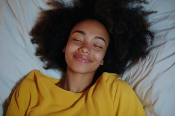 Wall Mural - A woman with curly hair is smiling and resting her head on a pillow. Concept of relaxation and comfort