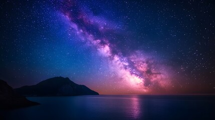 Night sky reveals vibrant Milky Way over mountain silhouette and ocean, featuring deep blue cosmic background with purple nebula colors, creating dreamy celestial scene with twinkling stars.