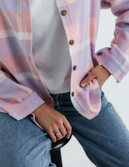 Portrait of a cute girl model in a pink checkered shirt and jeans in the studio on a white background